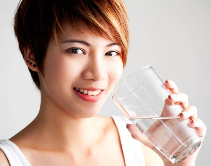 Woman drinking glass of pure water.