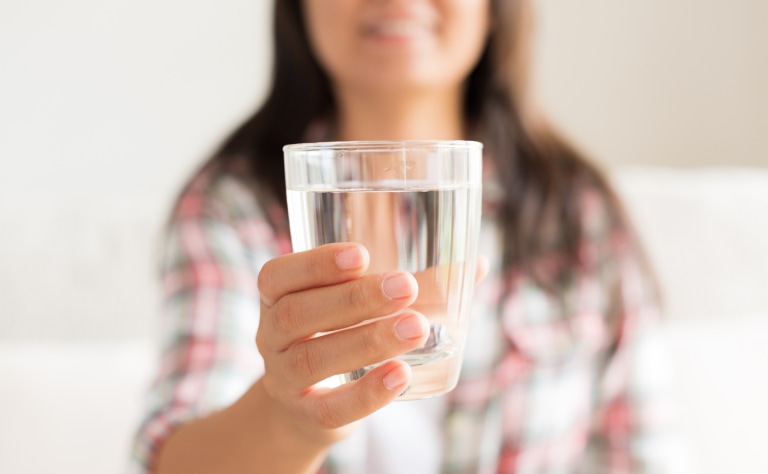 Woman holding out glass of water.