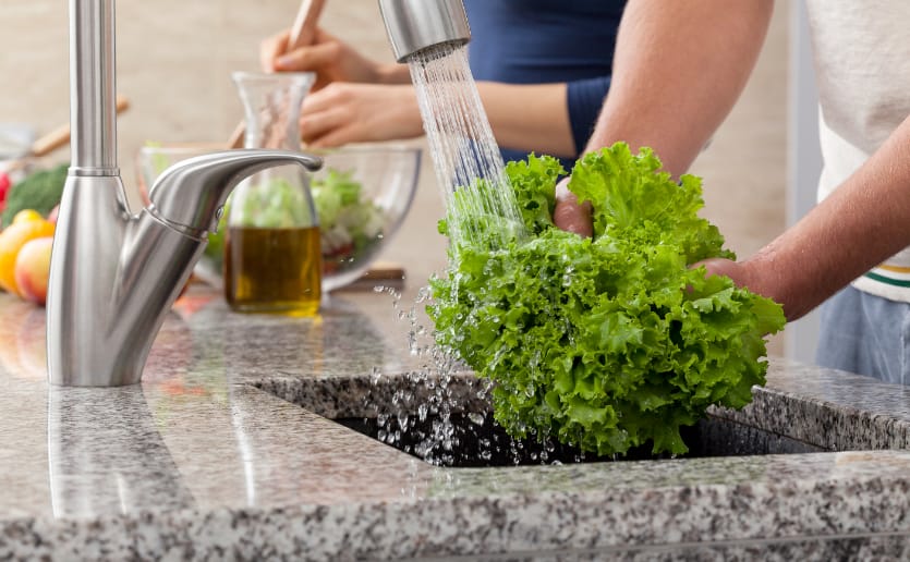 Washing lettuce in kitchen sink at home.