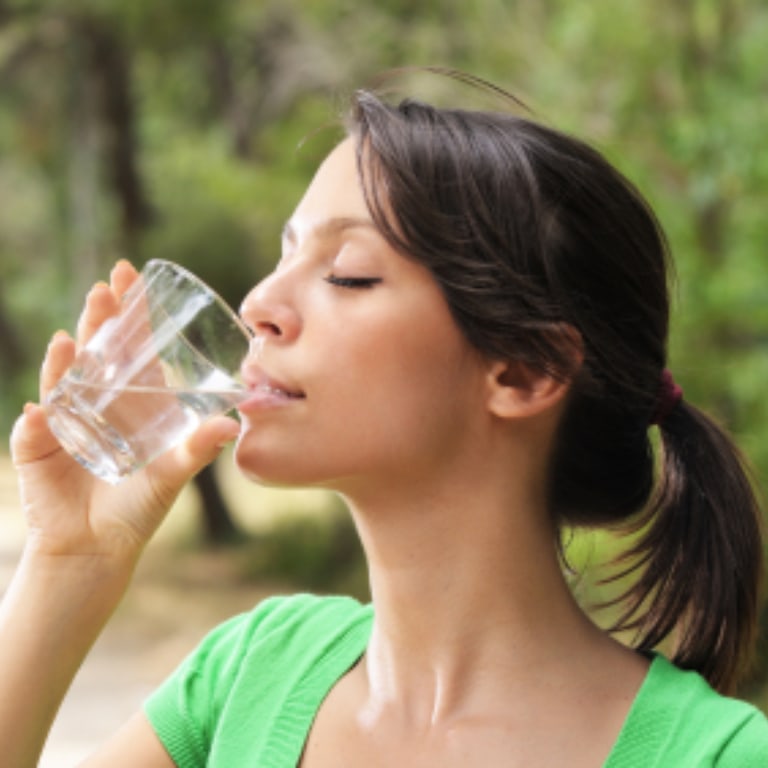 Woman drinking glass of water ourdoors