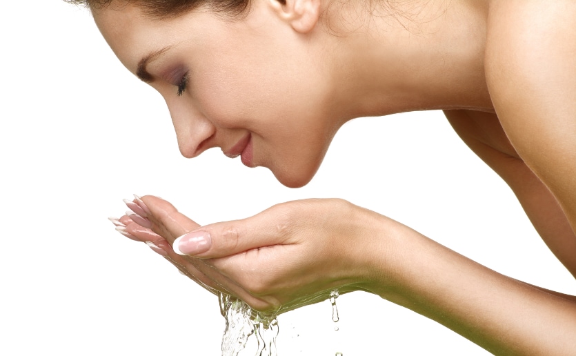 Woman washing face with clean water.