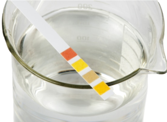 pH litmus strips on a beaker.